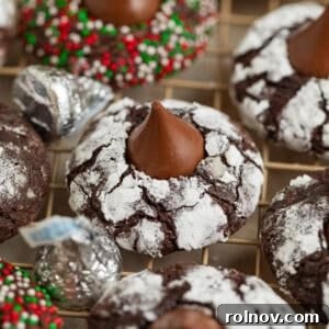 Chocolate crinkle cookies with hershey kiss centers on wire rack.