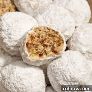 Pecan snowball cookies with powdered sugar on plate with bite taken out of one cookie.