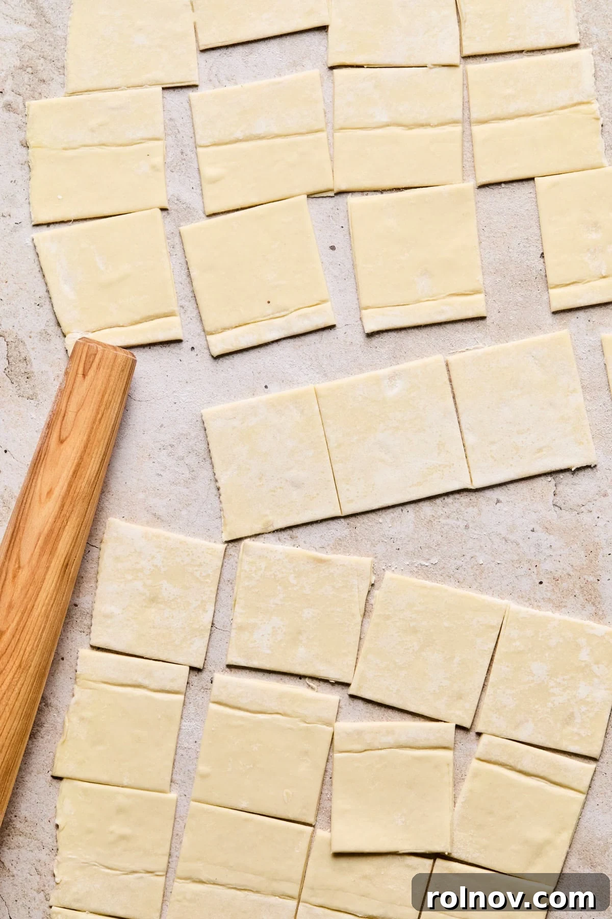 Golden Brie Pastry Parcels 4 Thawed puff pastry sheet on a cutting board, being cut into squares with a pizza cutter.