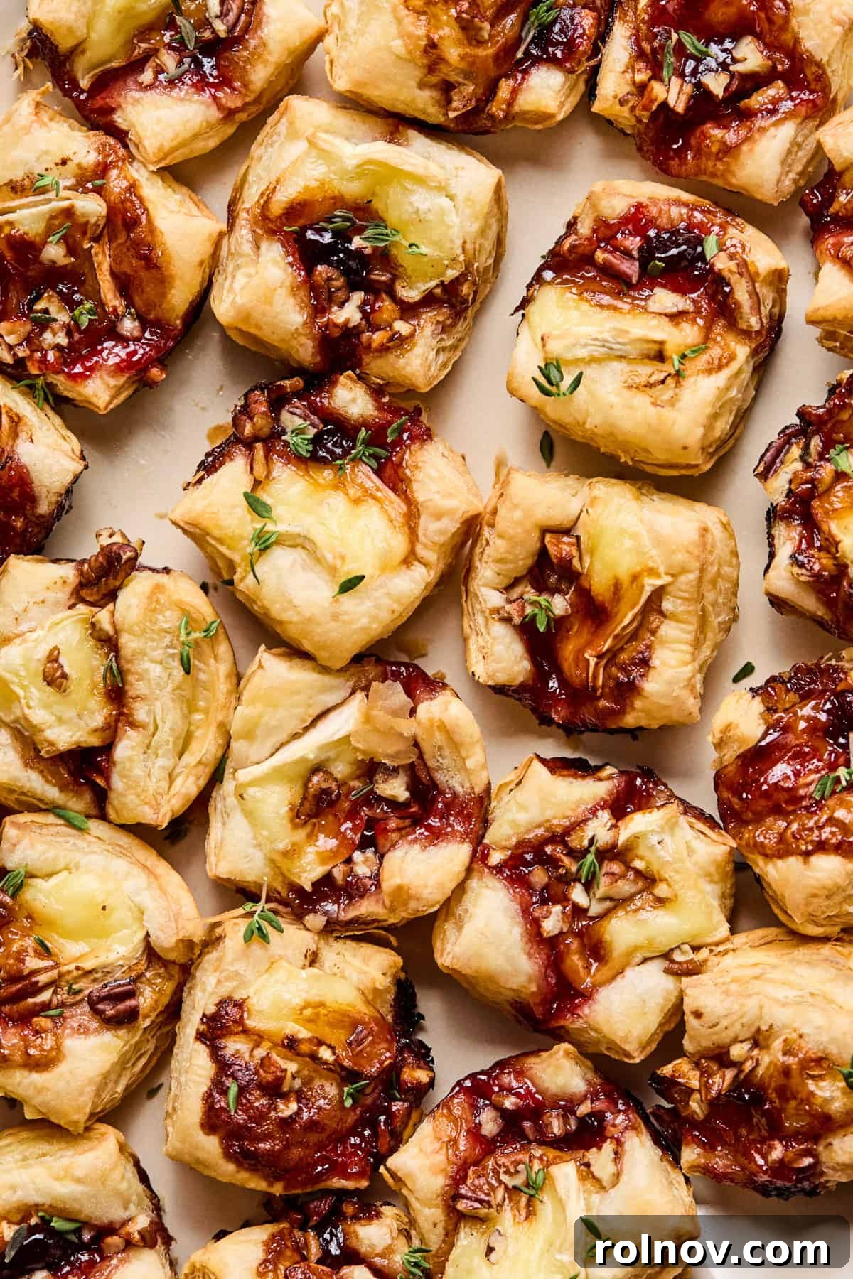 Golden Brie Pastry Parcels 8 Close-up overhead view of several baked puff pastry brie bites on a white platter.
