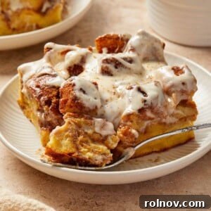 Slice of Brioche French toast bake with cinnamon and cream cheese frosting on plate.