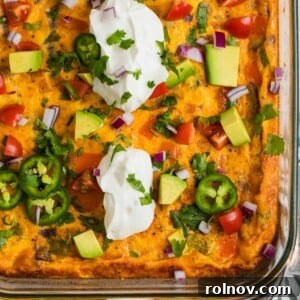 Chorizo egg bake in glass baking pan topped with sour cream, jalapeño, and avocado.