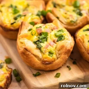 Mini quiches with puff pastry on a wooden board, topped with onion and chopped parsley.