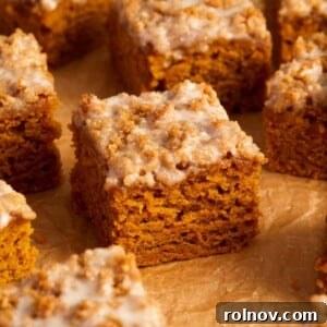 Slices of cinnamon streusel topped pumpkin coffee cake on crinkled brown parchment paper.
