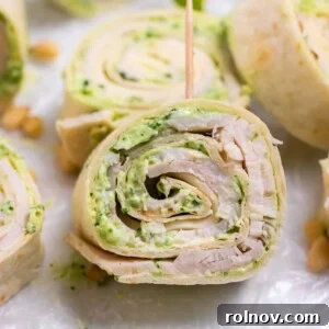 Delicious Pesto Turkey Pinwheels, neatly rolled and secured with a toothpick, showcasing layers of turkey, pesto, and smoked provolone.