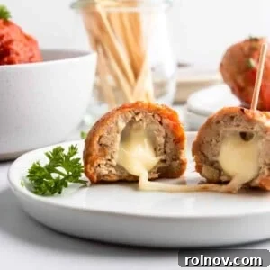 Delectable mozzarella stuffed turkey meatballs on a plate, with stringy melted cheese pulling apart, showcasing their cheesy core.