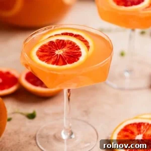 A vibrant, effervescent glass of Blood Orange Champagne Sangria, garnished with fresh fruit, perfect for festive celebrations.