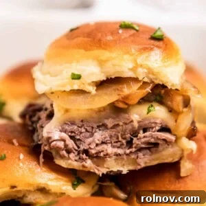 Mouth-watering roast beef sliders, generously topped with melted cheese, caramelized onions, and tender mushrooms, ready for dipping.