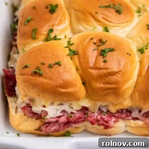 Classic Slow Cooker Reuben sliders prepared in a white baking pan, featuring tender corned beef and melty cheese.