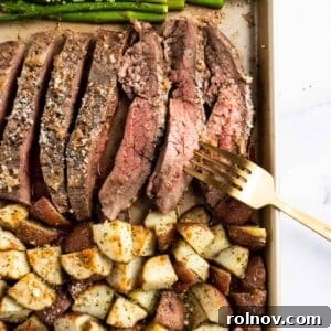 A hearty Parmesan Crusted Steak and Potato Sheet Pan Dinner featuring perfectly cooked flank steak slices, crispy roasted potatoes, and fresh asparagus, all arranged on a baking sheet.