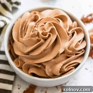 Luxurious chocolate whipped cream, beautifully piped into a white bowl, hinting at its rich and airy texture, perfect for any dessert.