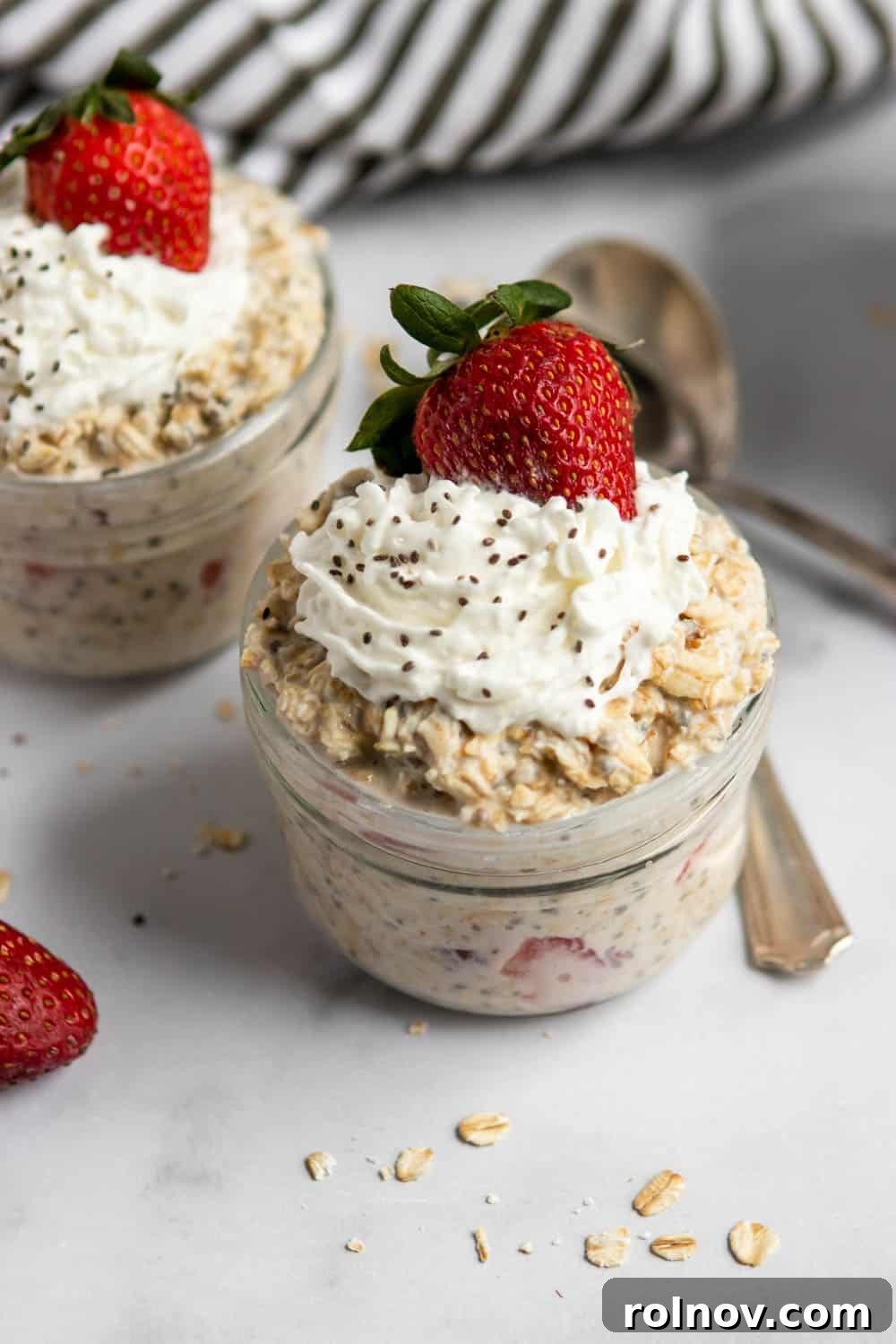 Dreamy Strawberry Shortcake Overnight Oats 5 Ingredients for Strawberry Shortcake Overnight Oats laid out on a wooden surface: strawberries, oats, milk, maple syrup, cashew butter, chia seeds, vanilla extract, and salt.