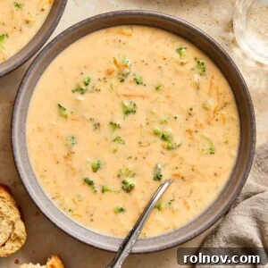 Gray ceramic bowl with broccoli cheddar soup served with spoon.