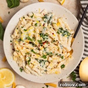Plate with creamy pasta topped with chopped parsley and lemon zest.