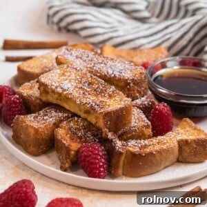 Plate of golden-brown air fryer French toast sticks generously dusted with powdered sugar.