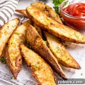 Crispy air fried potato wedges, perfectly golden brown, served with a side of vibrant red ketchup.