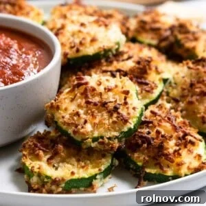 Crispy cheese-coated zucchini slices on a plate, ready to be enjoyed.