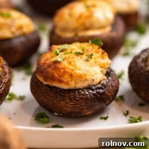 Air fried stuffed mushrooms arranged on a white plate, elegantly topped with chopped fresh parsley.