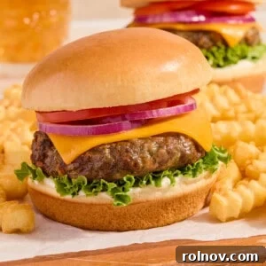 Perfectly air fried hamburger on a bun, accompanied by a side of crispy french fries, resting on a parchment-lined wooden surface.