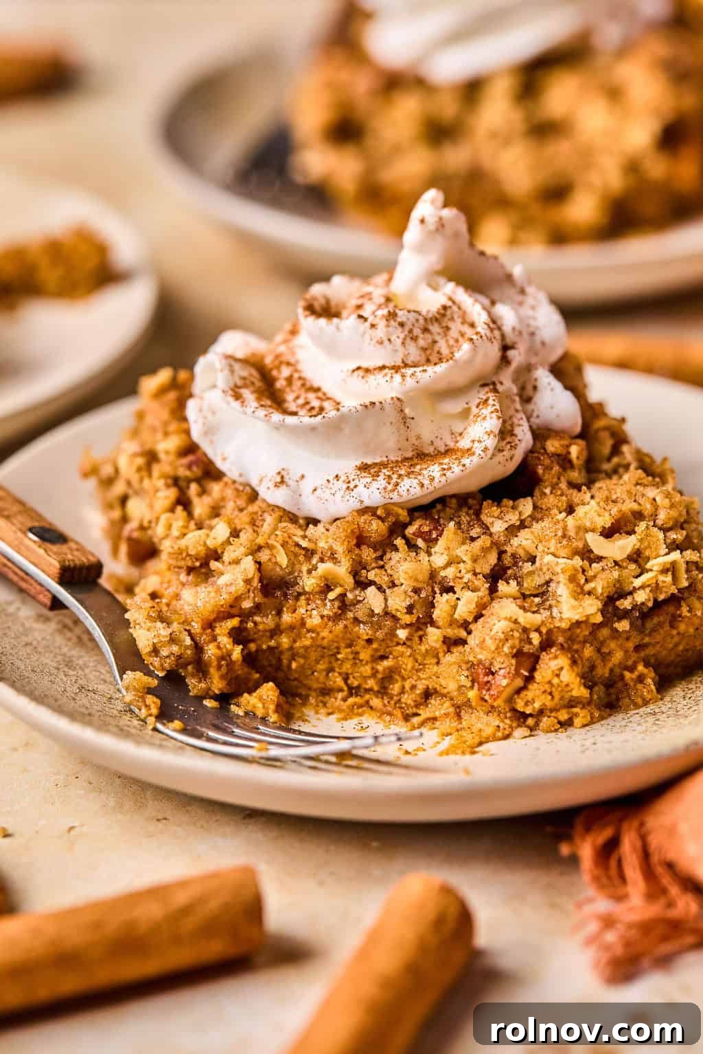 Spiced Pumpkin Crumble 2 Pumpkin pie crumble slice on plate with whipped cream on top and fork propped beside it.
