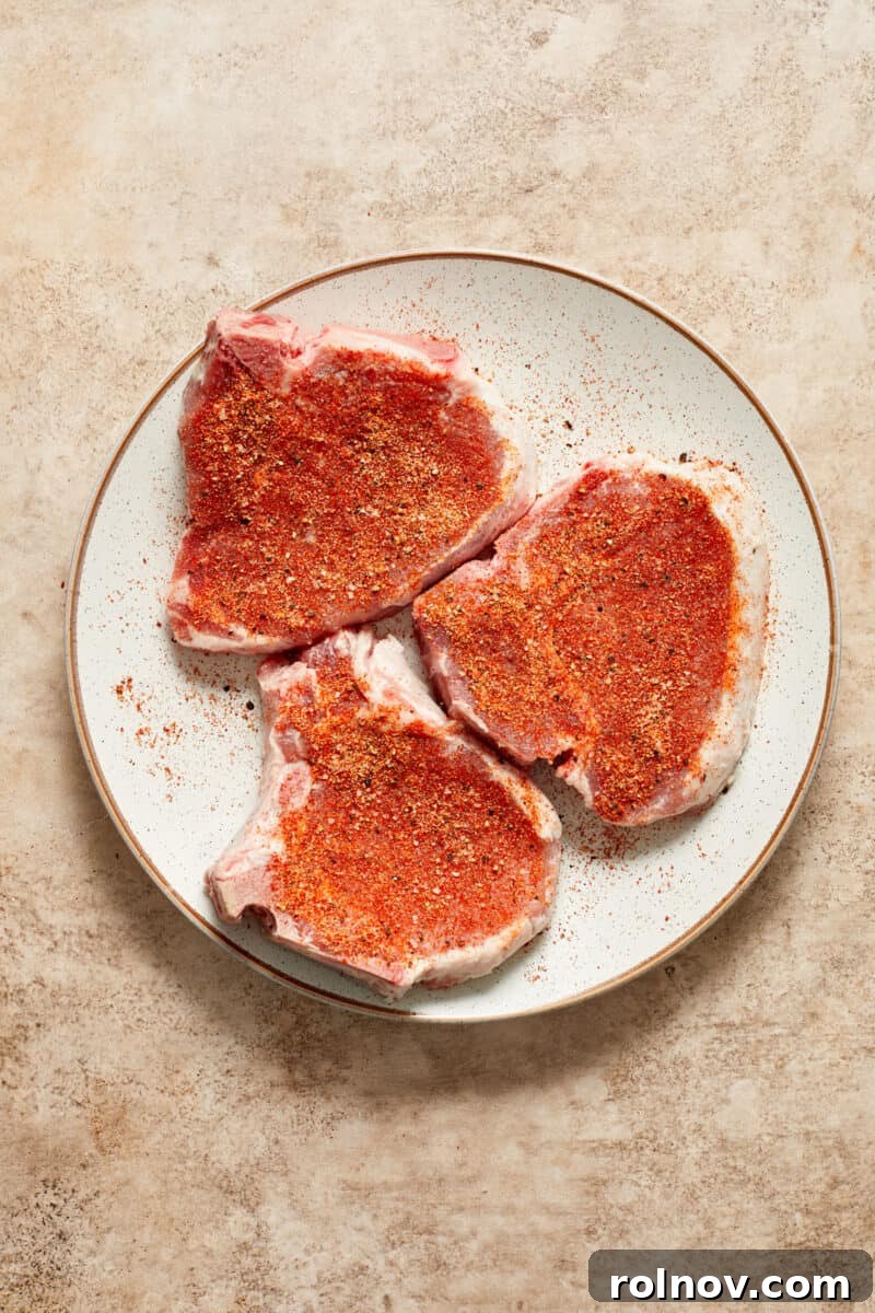 Velvety Mushroom Pork Chops 8 Pork chops with seasoning on white plate.