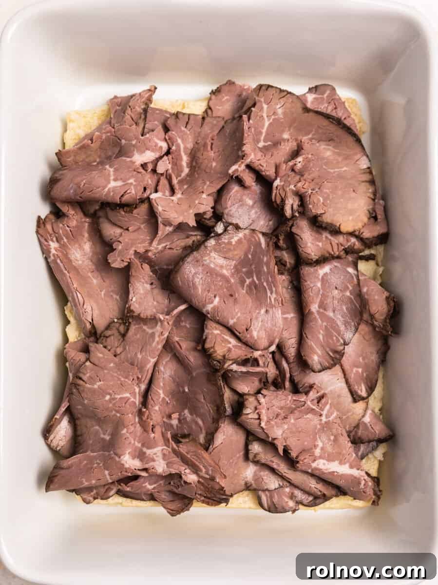 Ultimate French Dip Sliders 6 Generous slices of roast beef layered evenly on top of Hawaiian rolls in a baking dish.