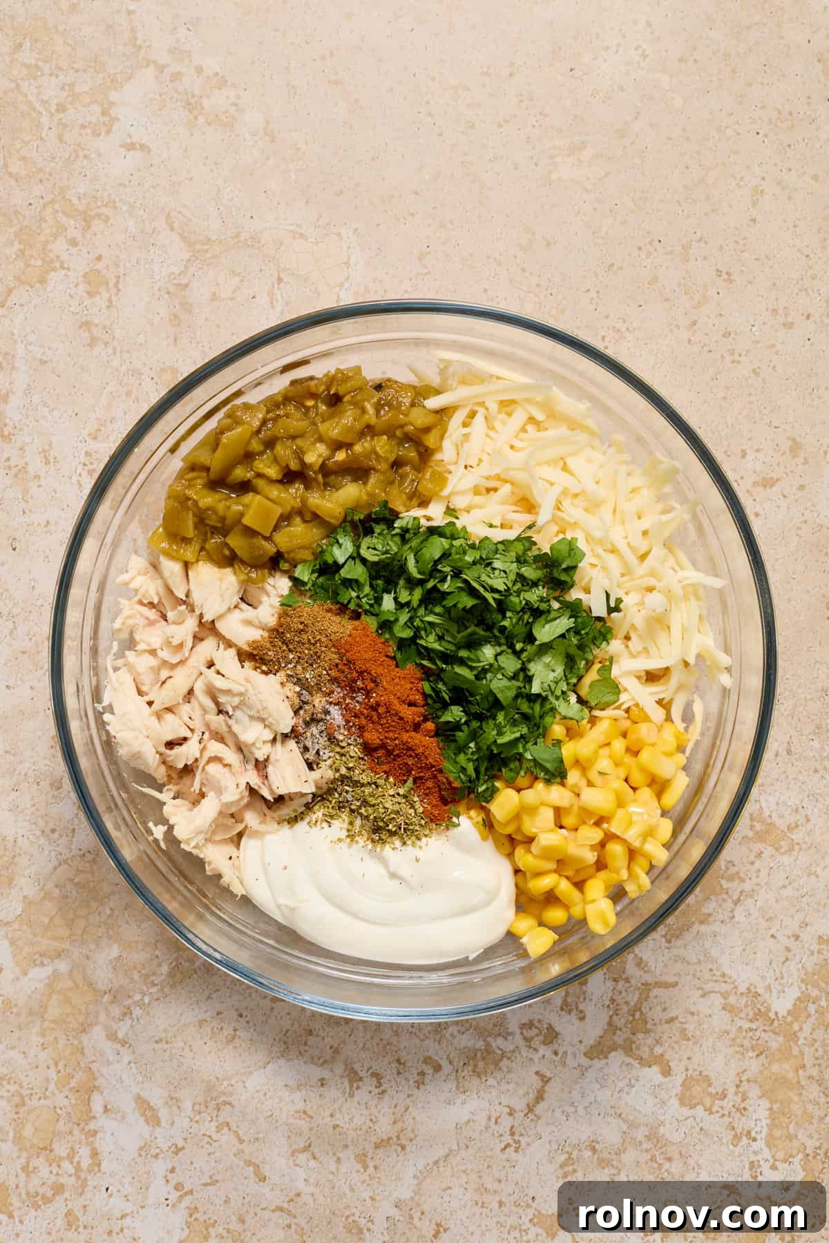 Zesty Verde Chicken Enchiladas 4 Chicken, cilantro, corn, spices, sour cream, cheese and other ingredients for chicken enchiladas in bowl.
