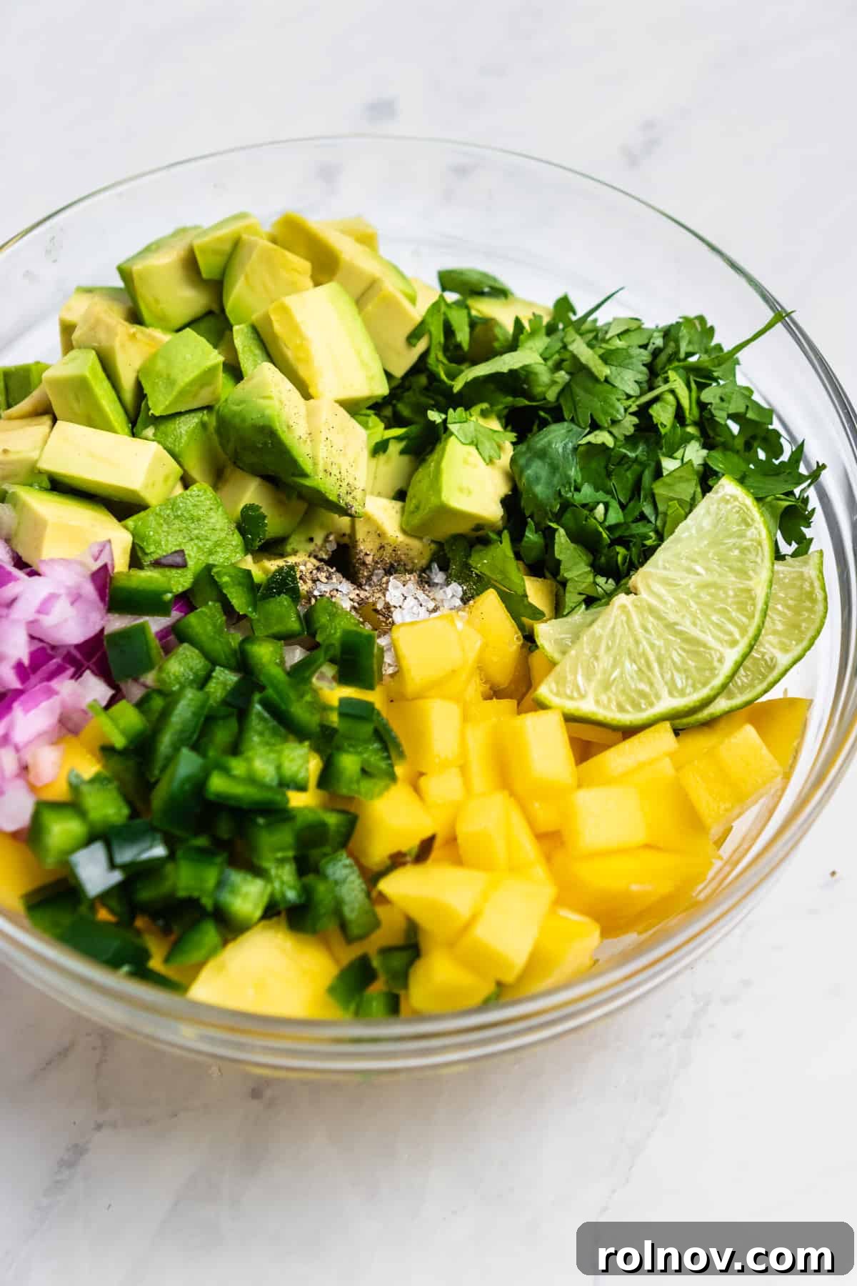Close-up view of vibrant Mango Avocado Salsa in a clear glass mixing bowl, showcasing the fresh diced ingredients combined.