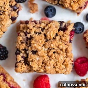 Mixed berry bar with oat crumble topping on parchment.