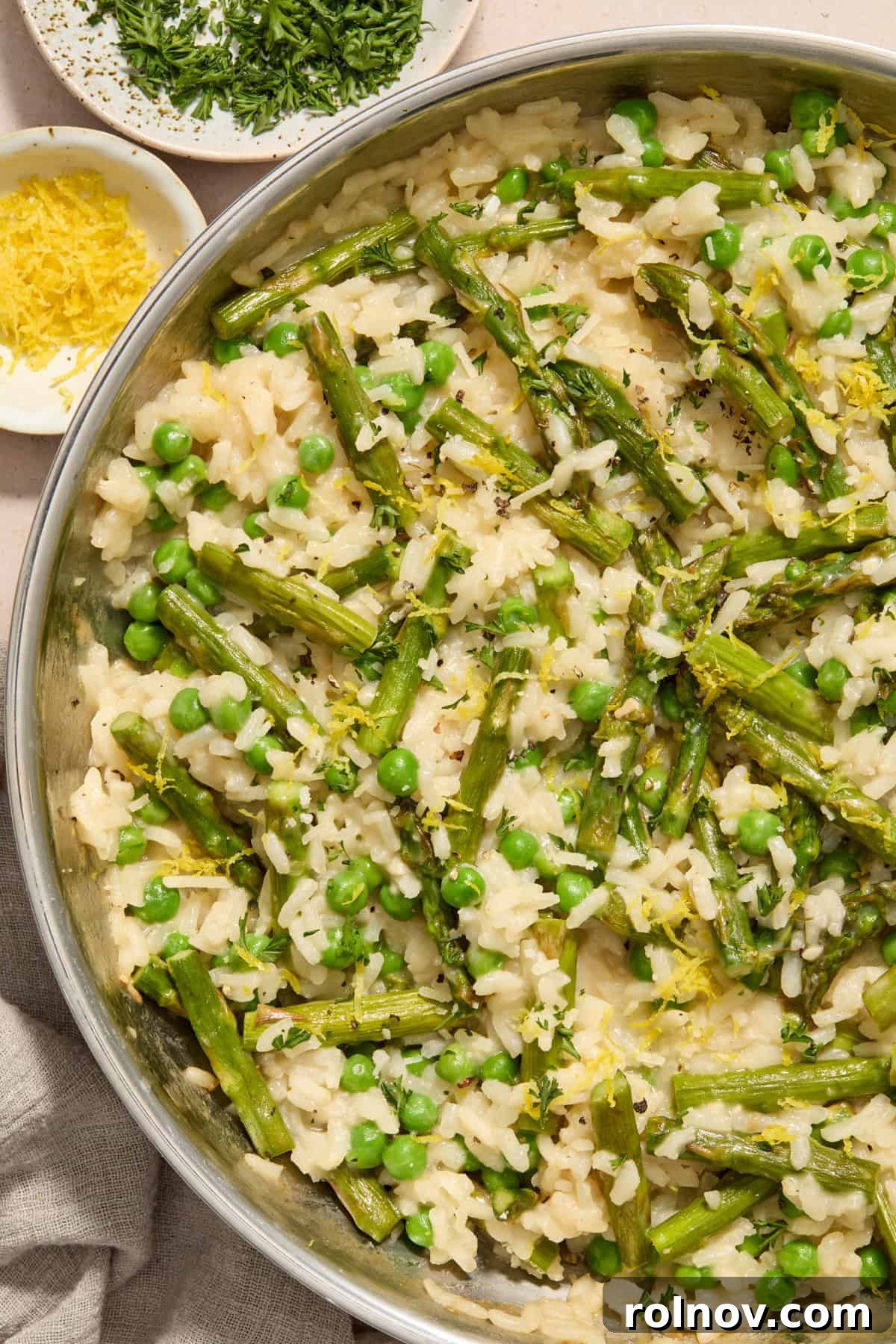 Springtime Pea and Asparagus Risotto 2 Creamy risotto with peas and asparagus in pan topped with parmesan and lemon zest.