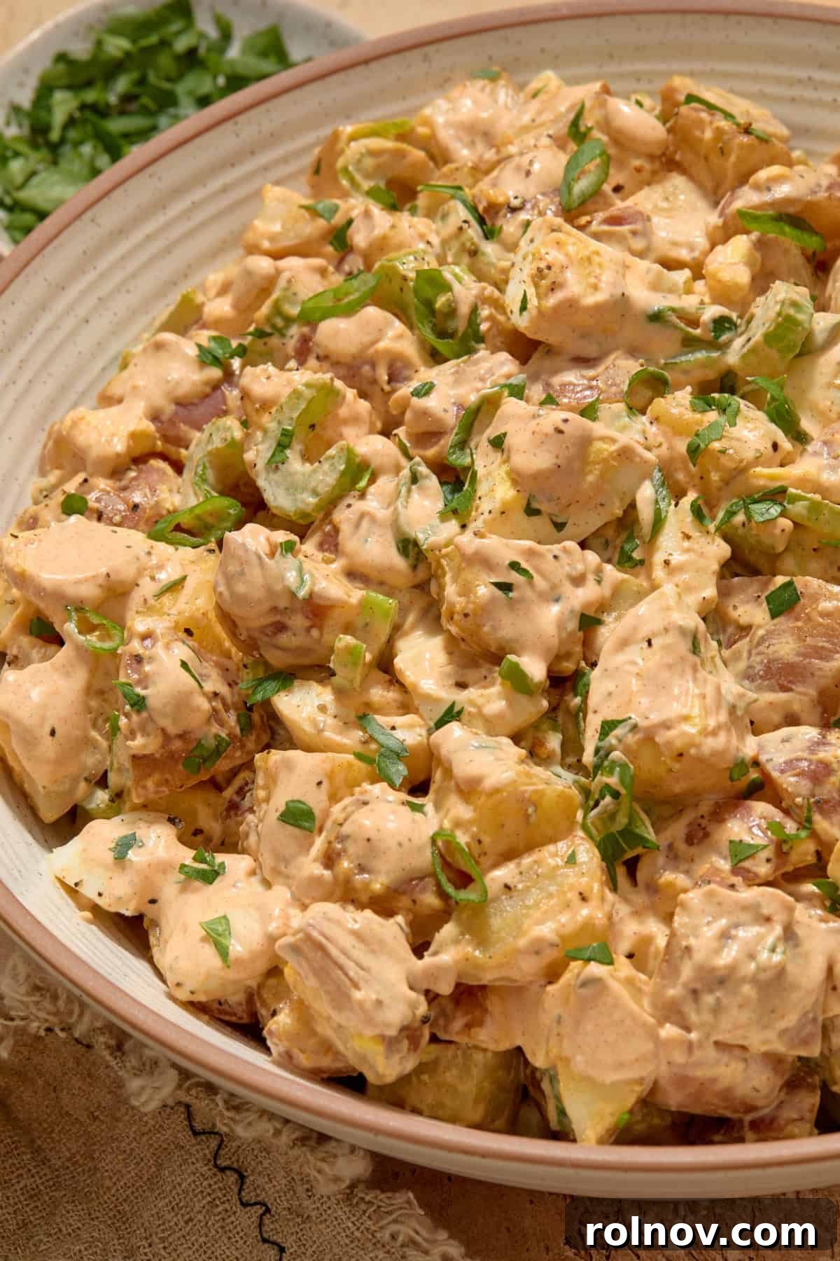 Bayou Potato Salad 10 Cajun potato salad in a large serving bowl, generously topped with chopped fresh parsley for garnish.