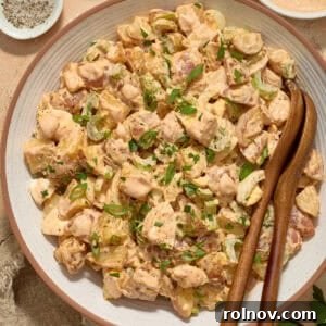 Serving bowl with potato salad and serving utensils.
