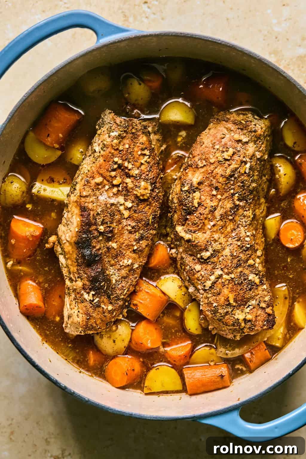 Succulent Dutch Oven Pork Tenderloin 7 Cooked and glazed pork tenderloin in pot with carrots and potatoes.