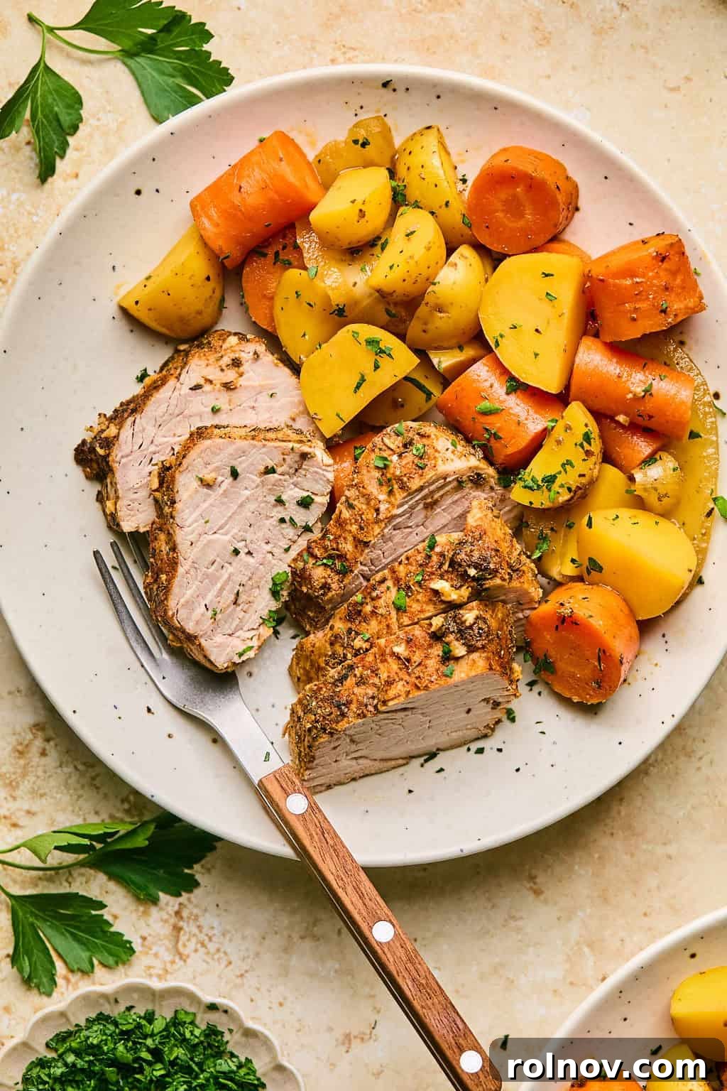 Succulent Dutch Oven Pork Tenderloin 8 Plate with sliced pork tenderloin and carrots and potatoes.