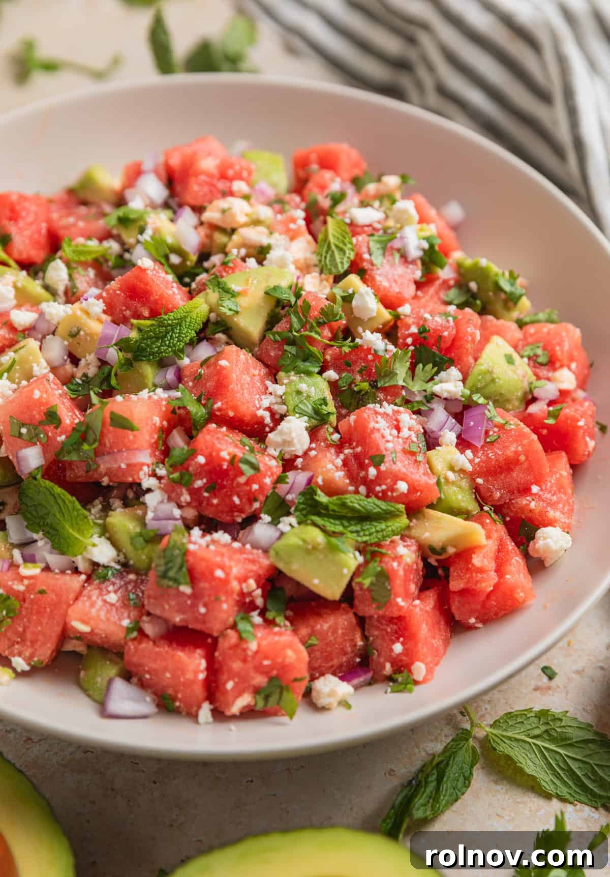 Watermelon Avocado Feta Harmony 3 Watermelon salad with perfectly cubed avocado and crumbled feta, garnished with fresh cilantro and mint leaves in a serving bowl.