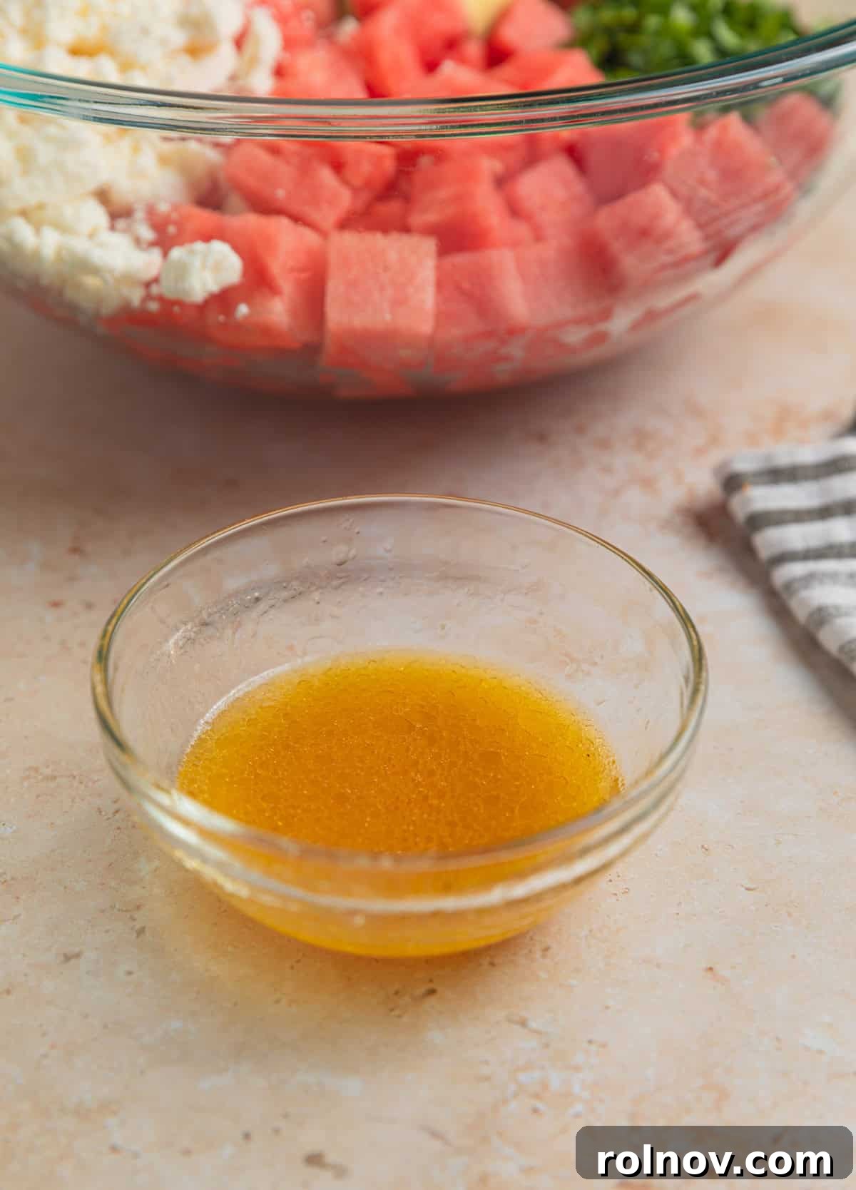 Watermelon Avocado Feta Harmony 6 A small dish containing whisked olive oil, lime juice, and red wine vinegar, forming the salad dressing.