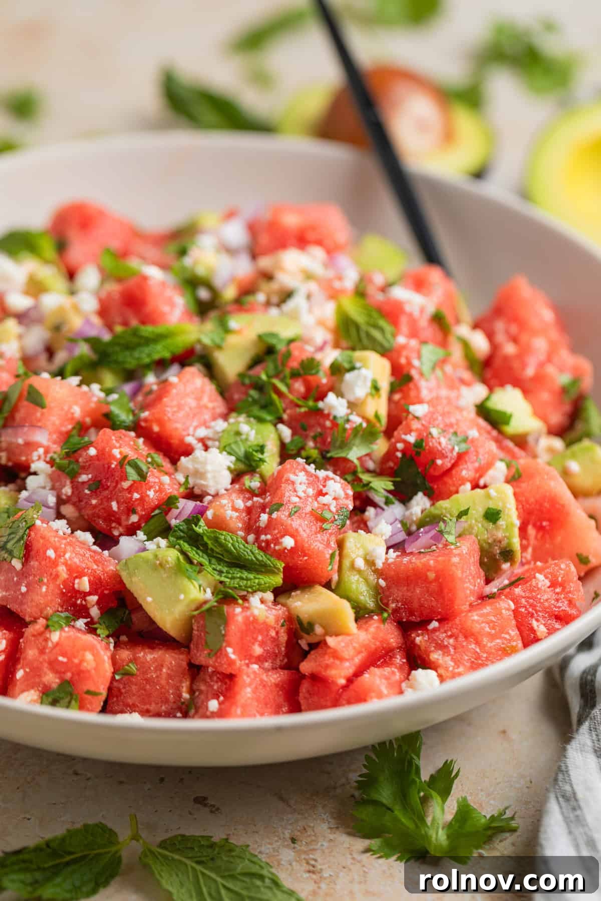 Watermelon Avocado Feta Harmony 9 A large salad bowl filled with the colorful watermelon, feta, and avocado salad, with a serving spoon resting inside.