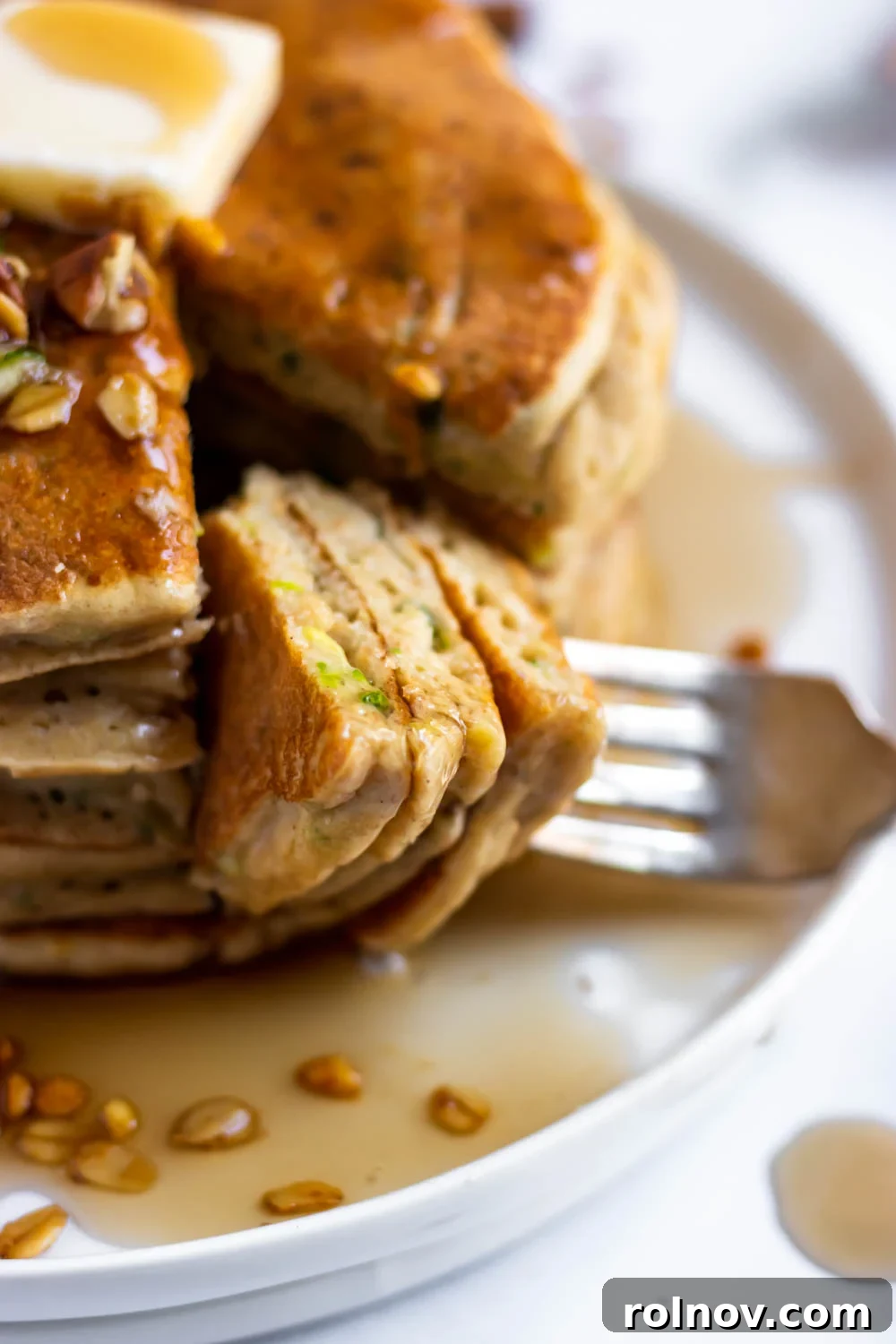 Wholesome Zucchini Oat Pancakes 3 A fork piercing a stack of zucchini oat flour pancakes, showing the green flecks of zucchini.