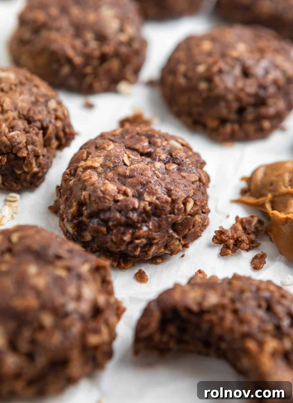 Cookie butter cookies laying on parchment with bite taken out of one cookie.