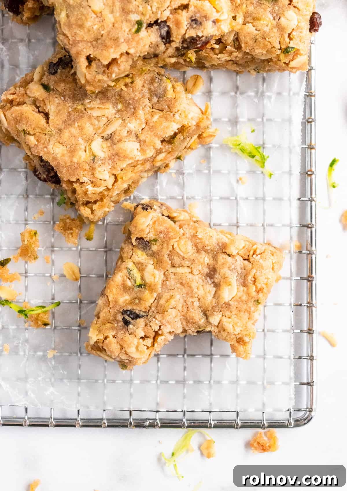 Freshly baked Zucchini Oatmeal Bars cooling on a wire rack, sprinkled with a touch of powdered sugar.