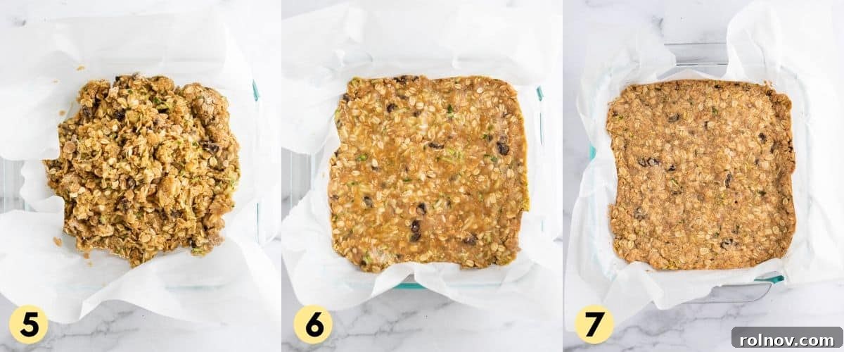 The zucchini and oat mixture has been pressed firmly into a parchment-lined 8x8 inch baking pan, ready for baking.