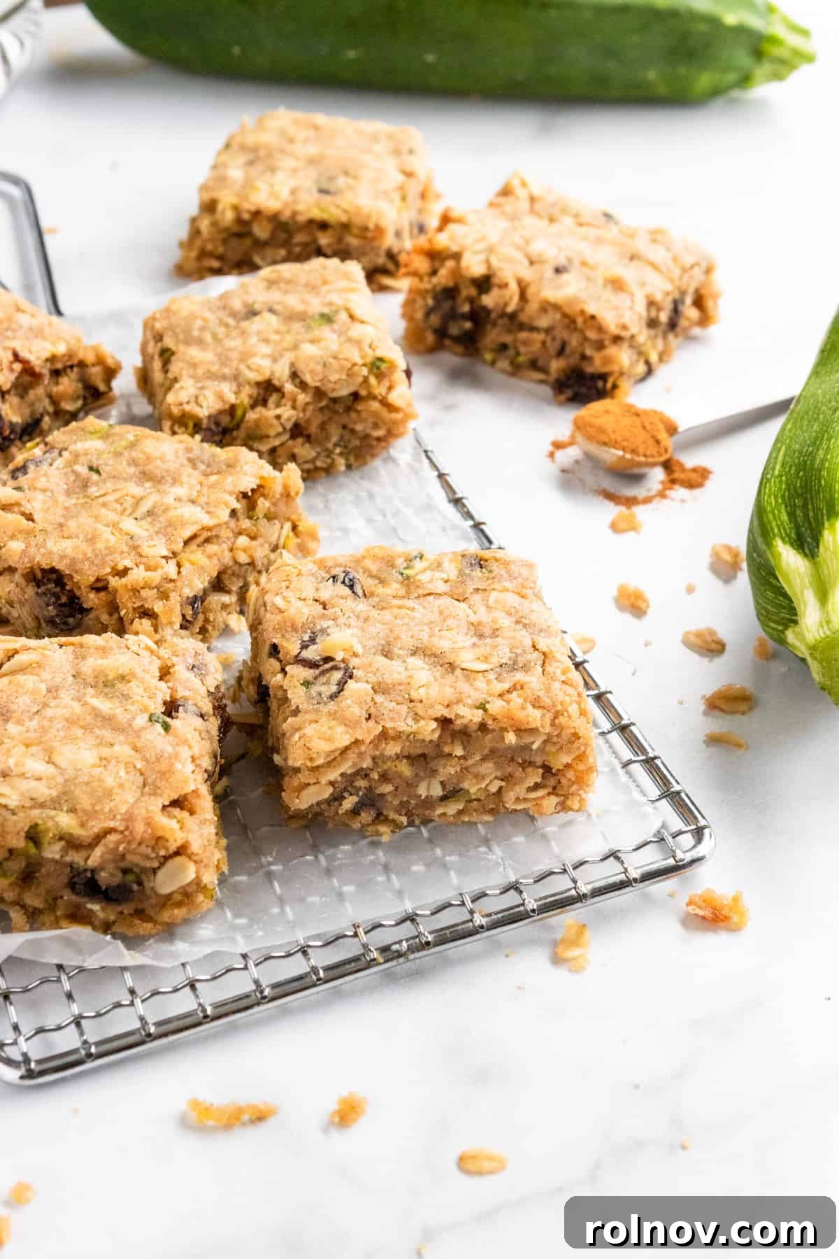 Delicious Zucchini Oatmeal Bars, cut into squares, arranged on a cooling rack with crumbs scattered around, highlighting their crumbly texture.