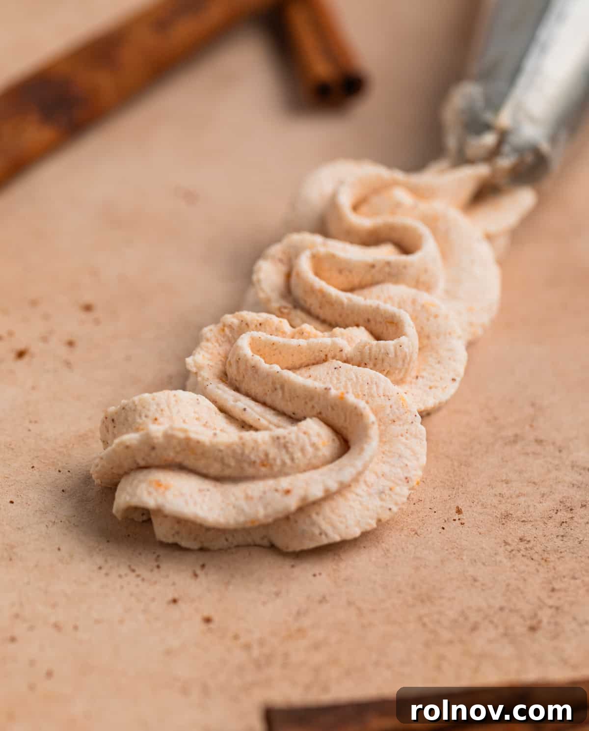Autumn's Pumpkin Cloud 8 Piped whipped cream on board with cinnamon sticks surrounding.