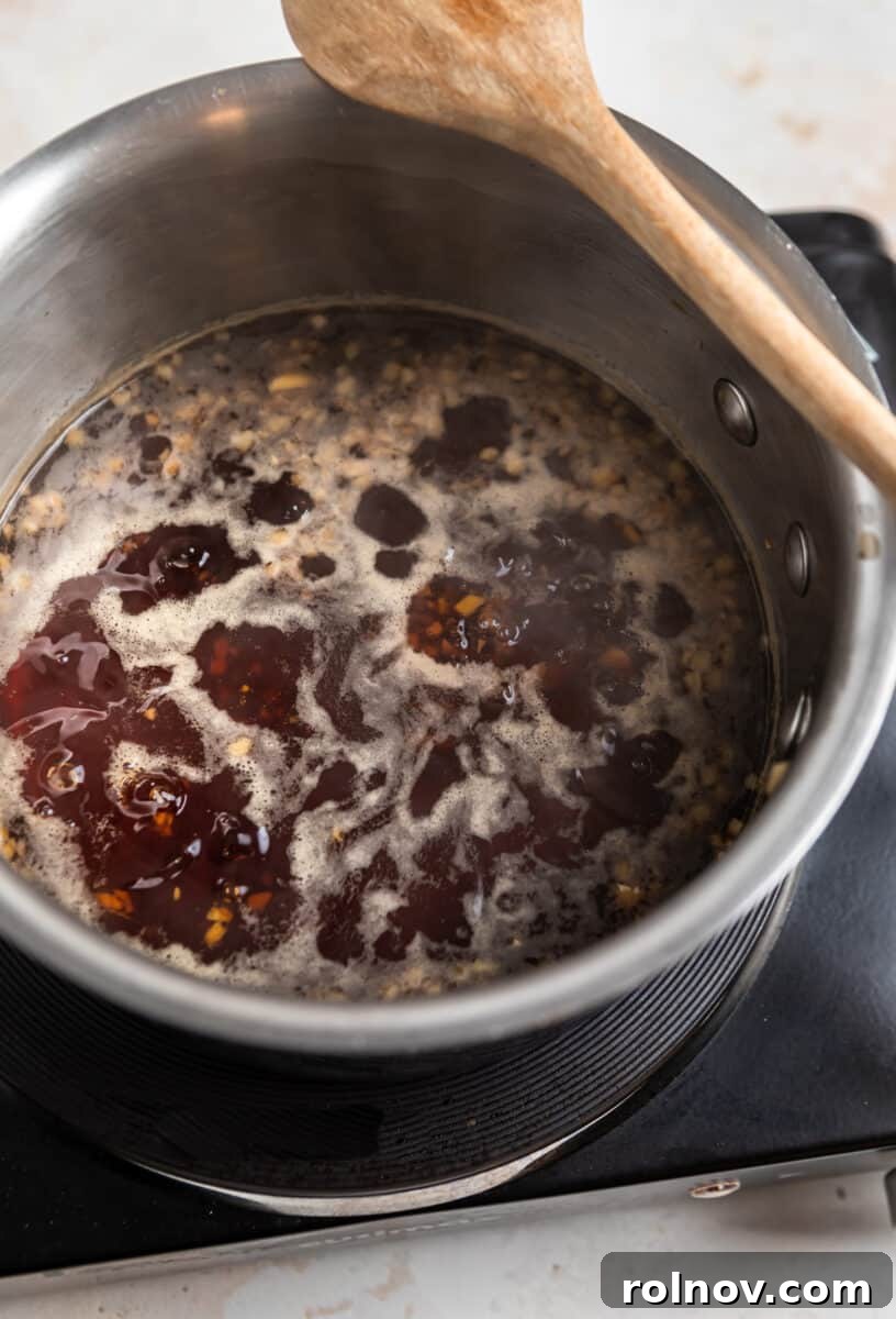 Sticky Teriyaki Pork Stir Fry 4 Teriyaki sauce simmering in a saucepan with a wooden spoon.
