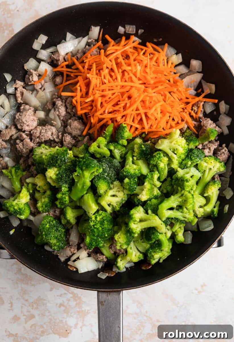 Sticky Teriyaki Pork Stir Fry 8 Frozen broccoli florets and shredded carrots added over the cooked ground pork and onion mixture in a skillet.