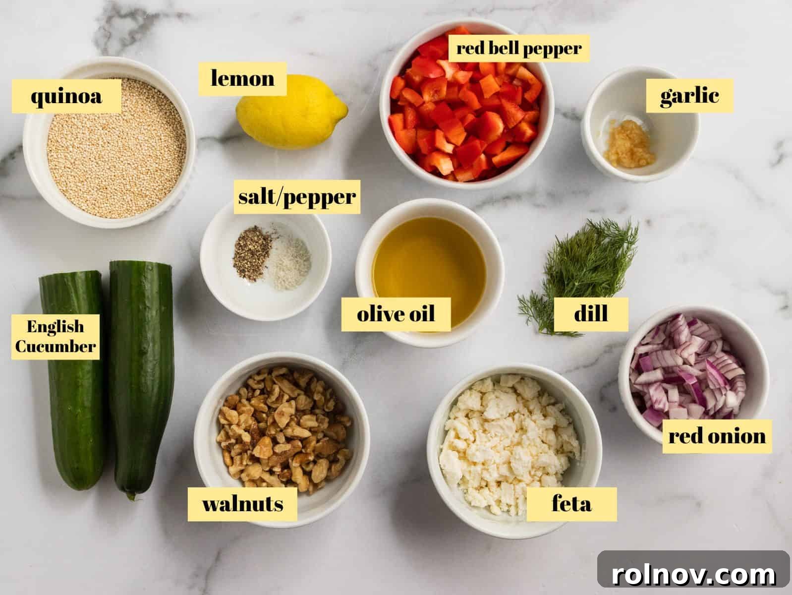 Zesty Cucumber Feta Quinoa Bowl 3 A flat lay photograph showcasing all the fresh ingredients needed for the Cucumber Quinoa Feta Salad, including uncooked quinoa, a red bell pepper, red onion, an English cucumber, feta cheese, garlic, a lemon, olive oil, walnuts, fresh dill, salt, and pepper.