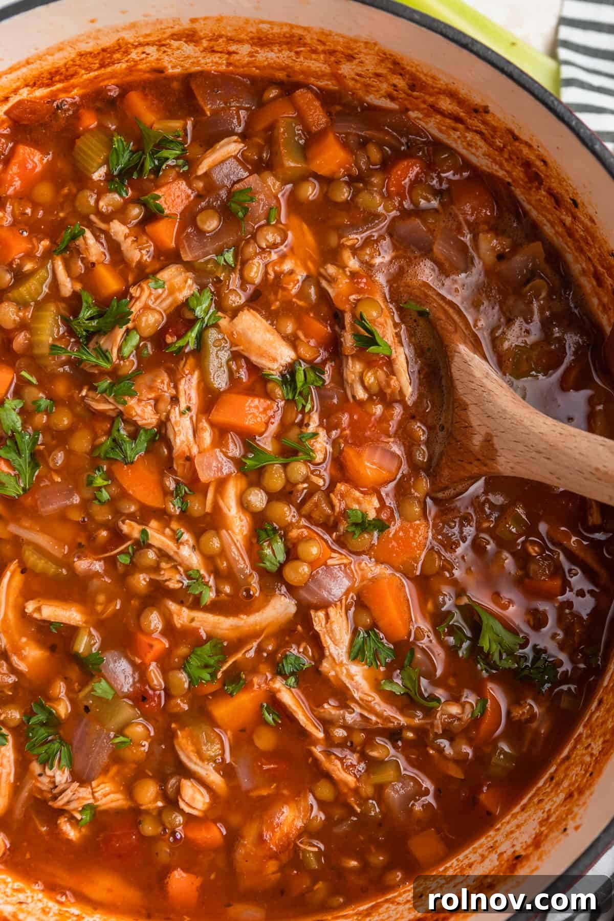 Turkey lentil soup in pot with wooden spoon.