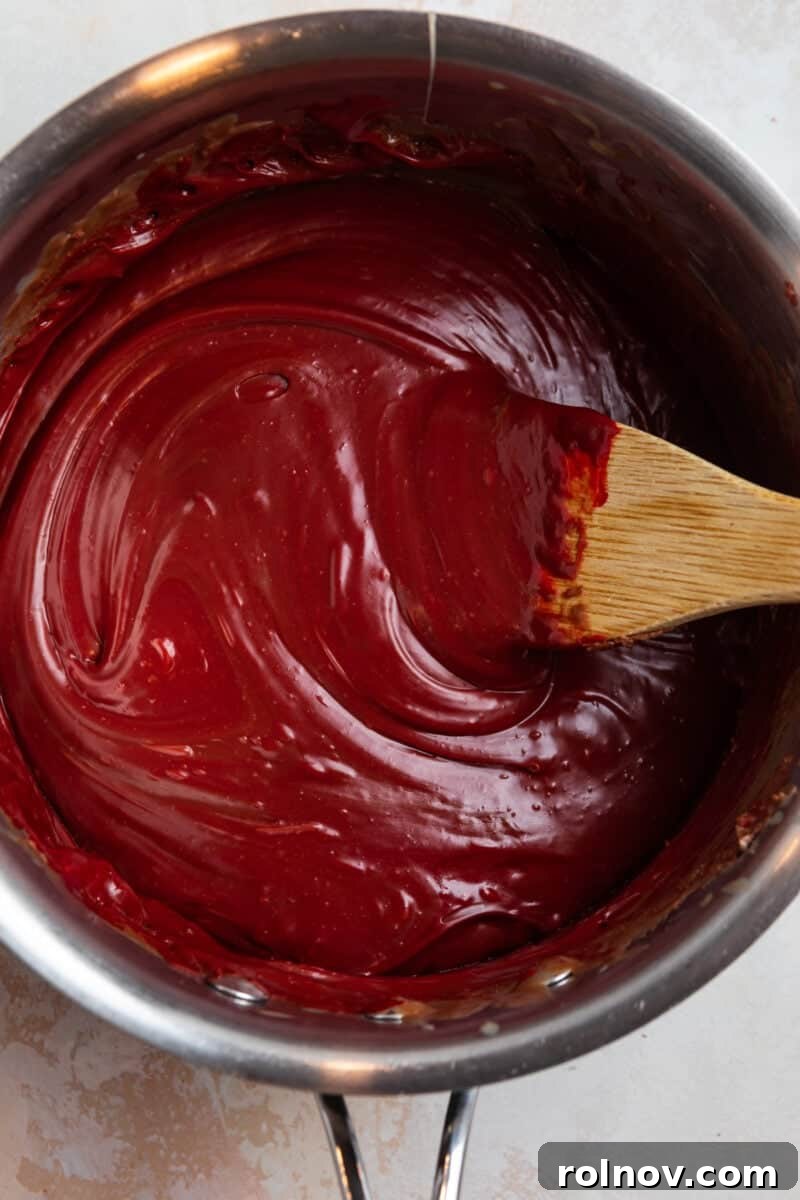 Red velvet fuge prepped in sauce pan with wooden spoon.