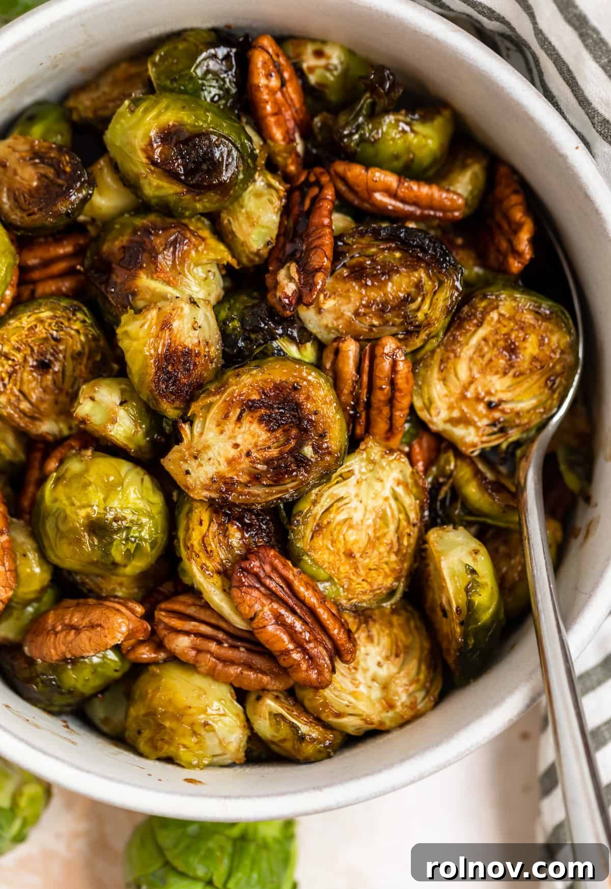 Perfect Pairings for Brussels Sprouts 2 Roasted maple balsamic brussels sprouts in dish with pecans, garnished with fresh herbs.