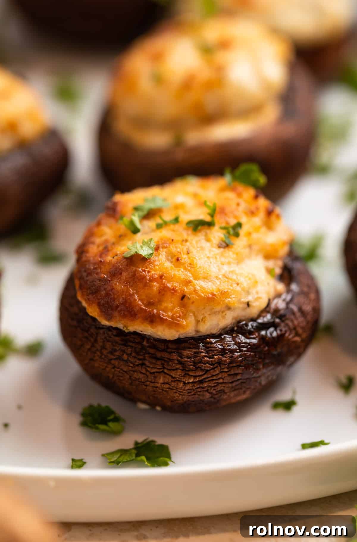 Savory Air Fryer Stuffed Mushrooms 2 Air fryer stuffed mushrooms on white plate topped with chopped parsley.